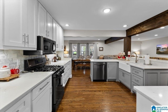 kitchen with appliances with stainless steel finishes, beamed ceiling, sink, white cabinetry, and tasteful backsplash