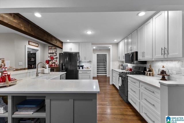 kitchen with appliances with stainless steel finishes, kitchen peninsula, dark hardwood / wood-style floors, white cabinets, and sink