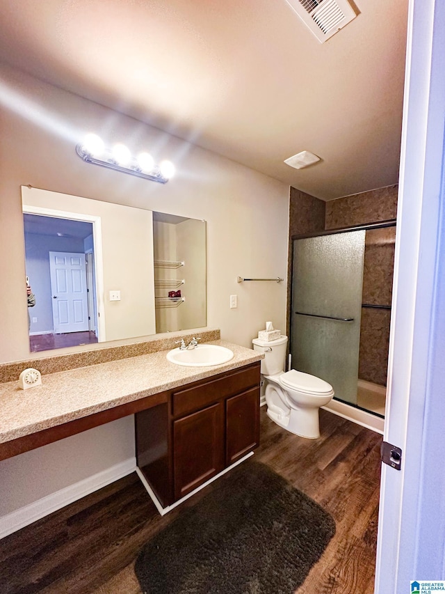 bathroom featuring vanity, toilet, hardwood / wood-style floors, and walk in shower