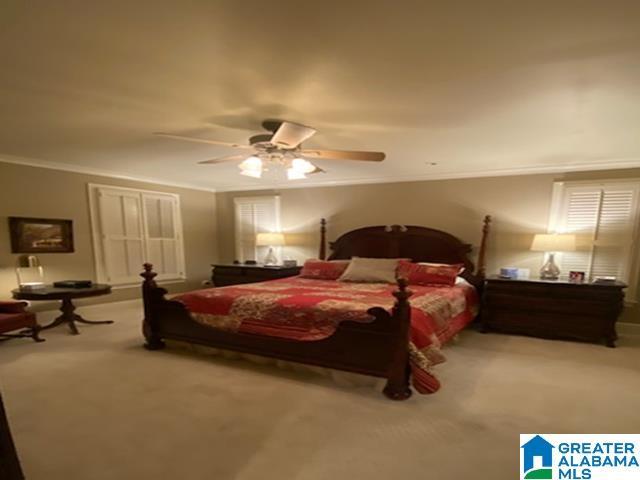 carpeted bedroom featuring ceiling fan and ornamental molding