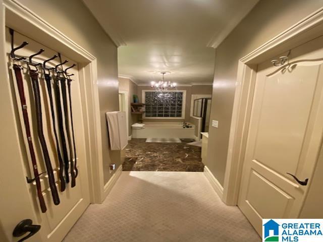 corridor with light carpet, a chandelier, and crown molding