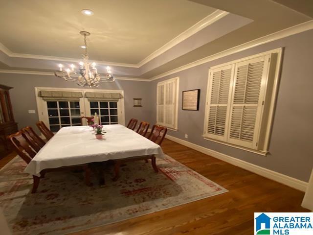 dining room featuring a raised ceiling, crown molding, hardwood / wood-style floors, and a notable chandelier