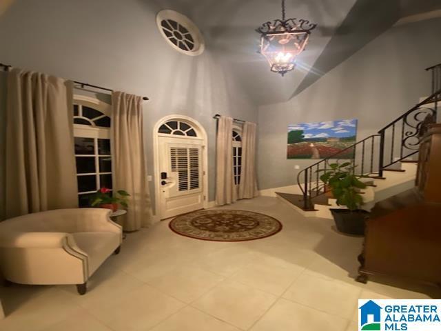 foyer entrance with high vaulted ceiling, a chandelier, and tile patterned floors