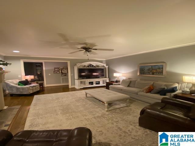 living room featuring crown molding, dark wood-type flooring, and ceiling fan