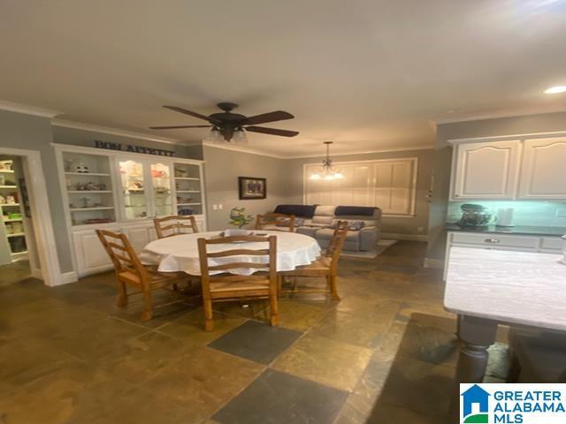 dining space with crown molding and ceiling fan with notable chandelier