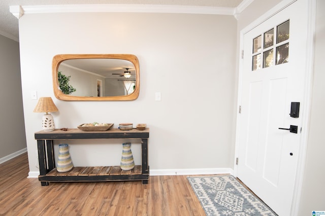 foyer featuring wood-type flooring, ceiling fan, and crown molding