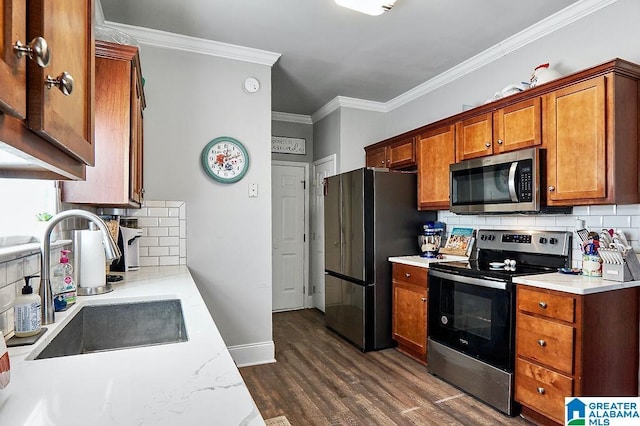 kitchen with dark wood-type flooring, sink, ornamental molding, appliances with stainless steel finishes, and backsplash