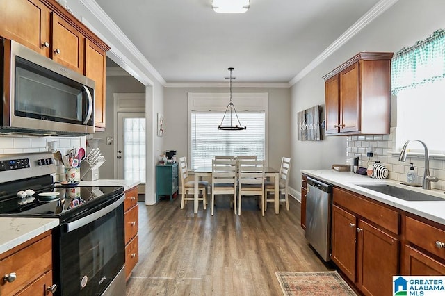 kitchen featuring stainless steel appliances, ornamental molding, hanging light fixtures, and sink