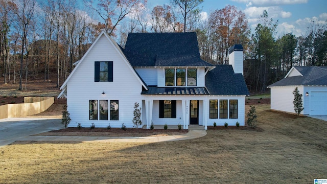 modern inspired farmhouse featuring covered porch, a front lawn, a garage, and an outdoor structure