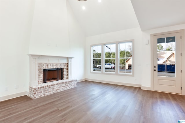 unfurnished living room with a brick fireplace, hardwood / wood-style floors, and high vaulted ceiling