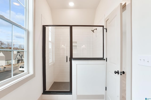 bathroom featuring a shower with shower door and a healthy amount of sunlight