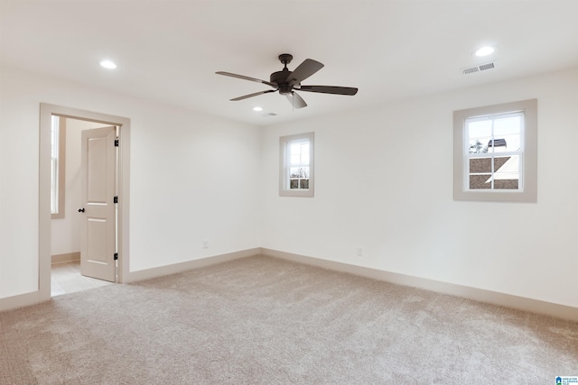 spare room featuring ceiling fan, light colored carpet, and a wealth of natural light