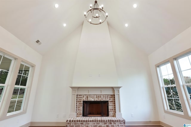 unfurnished living room with a brick fireplace, an inviting chandelier, and vaulted ceiling