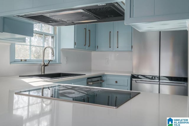 kitchen featuring exhaust hood, stainless steel fridge, black electric stovetop, blue cabinetry, and sink