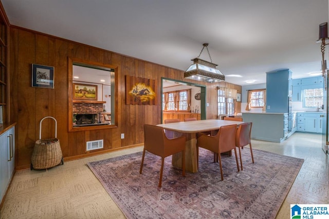 dining space featuring wood walls and a fireplace