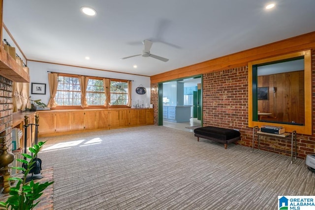 interior space featuring ceiling fan, ornamental molding, wood walls, carpet floors, and brick wall