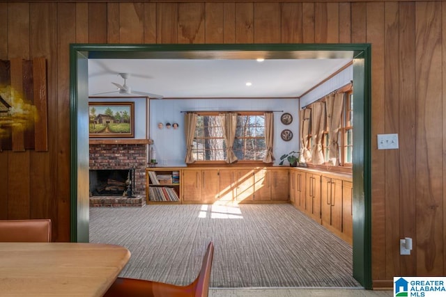 playroom featuring wood walls, ceiling fan, carpet, and a fireplace