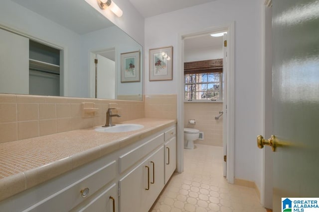 bathroom with toilet, tile walls, and vanity