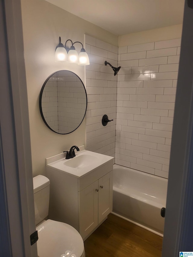 full bathroom with toilet, hardwood / wood-style flooring, tiled shower / bath combo, and vanity