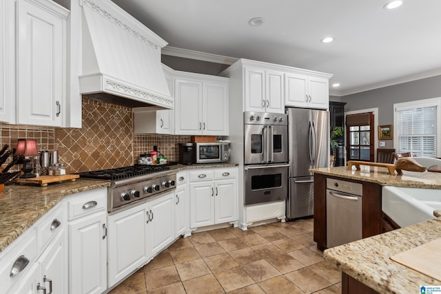 kitchen with custom exhaust hood, white cabinetry, crown molding, and stainless steel appliances