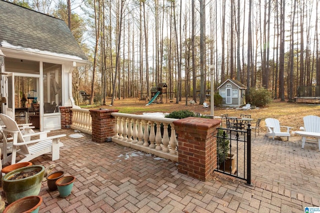 view of patio / terrace featuring a trampoline, a storage unit, a playground, and a sunroom