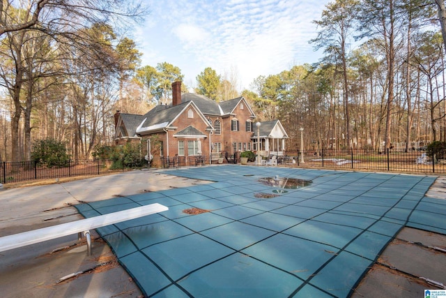 view of pool with a diving board and a patio