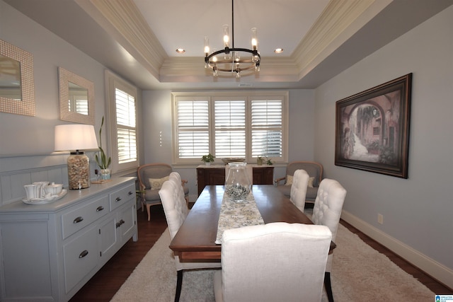 dining space with a notable chandelier, dark wood-type flooring, ornamental molding, and a raised ceiling