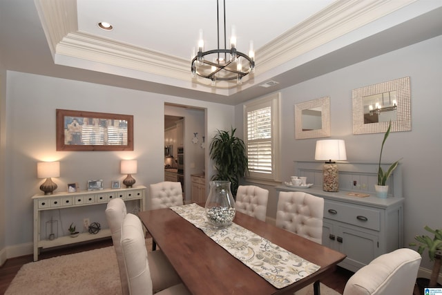 dining room featuring hardwood / wood-style floors, a raised ceiling, a chandelier, and ornamental molding