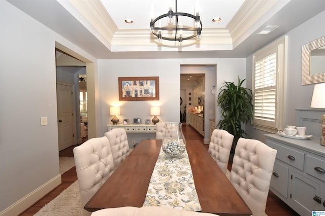 dining space with a raised ceiling, an inviting chandelier, crown molding, and dark wood-type flooring