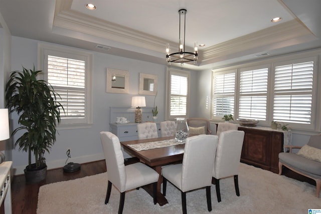 dining room with ornamental molding, light hardwood / wood-style flooring, an inviting chandelier, and a raised ceiling