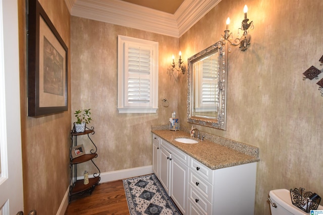 bathroom featuring toilet, vanity, hardwood / wood-style floors, and ornamental molding