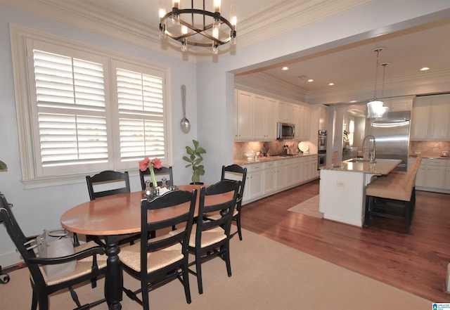 dining area featuring sink, dark hardwood / wood-style floors, crown molding, and a chandelier