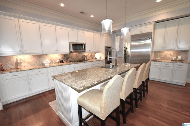 kitchen featuring white cabinetry, tasteful backsplash, a kitchen island with sink, and appliances with stainless steel finishes