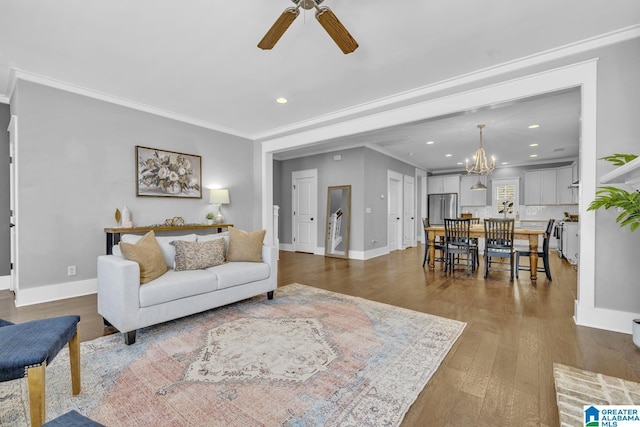 living room featuring ceiling fan with notable chandelier, ornamental molding, and wood-type flooring