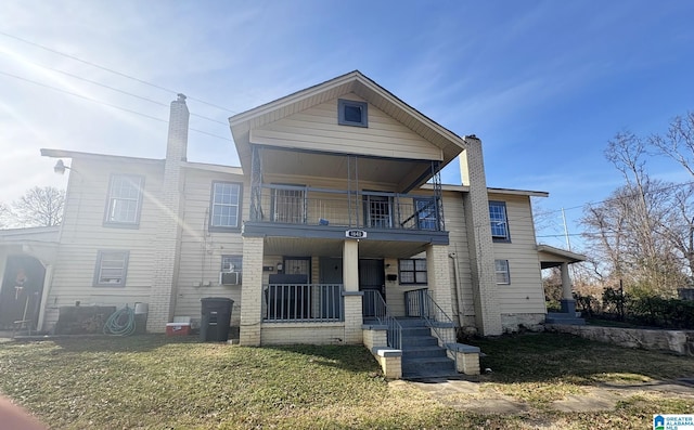 view of front facade with a balcony, a porch, and a front lawn