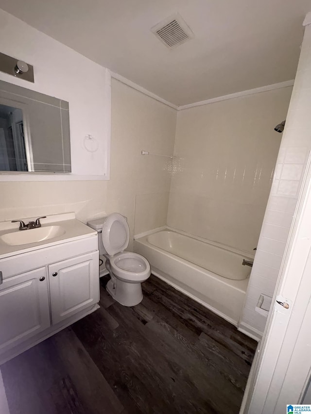 full bathroom with ornamental molding, hardwood / wood-style flooring, toilet,  shower combination, and vanity