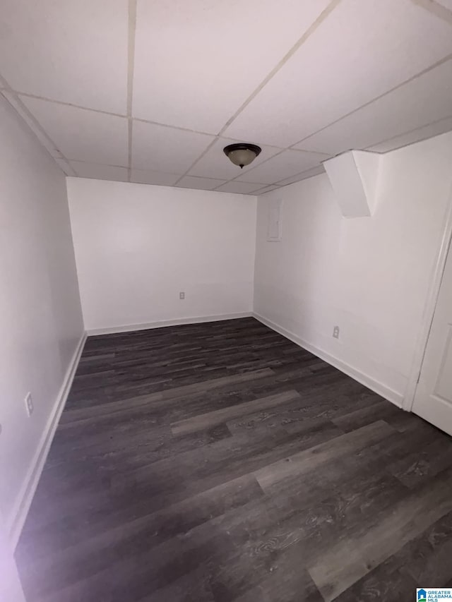 basement featuring a paneled ceiling and dark hardwood / wood-style floors