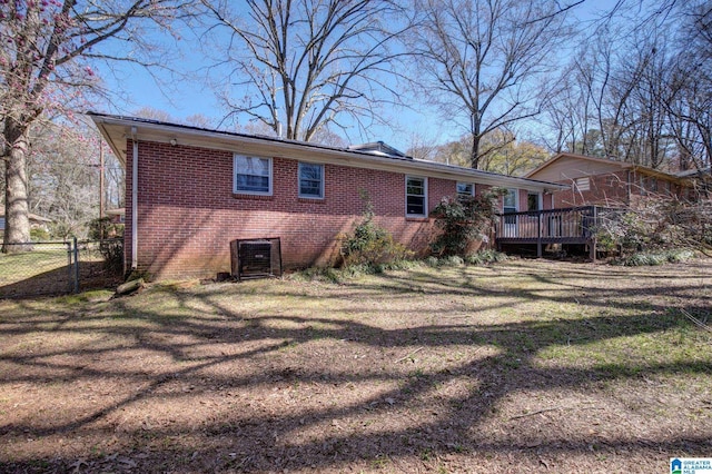 rear view of house featuring a deck, central air condition unit, and a lawn