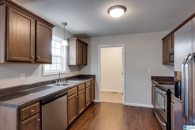 kitchen featuring sink, dark hardwood / wood-style floors, hanging light fixtures, and appliances with stainless steel finishes