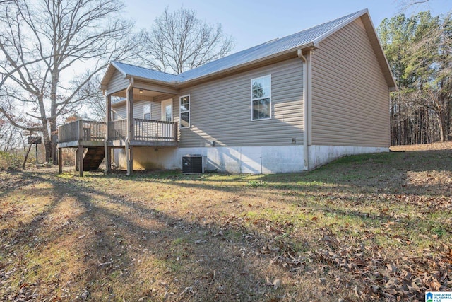 view of property exterior featuring cooling unit, a lawn, and a wooden deck