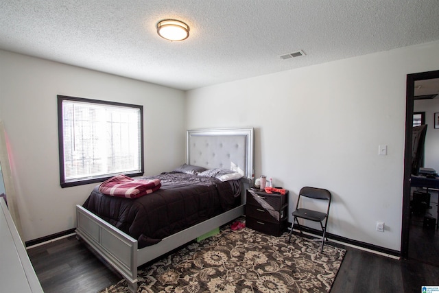 bedroom with a textured ceiling and dark hardwood / wood-style floors