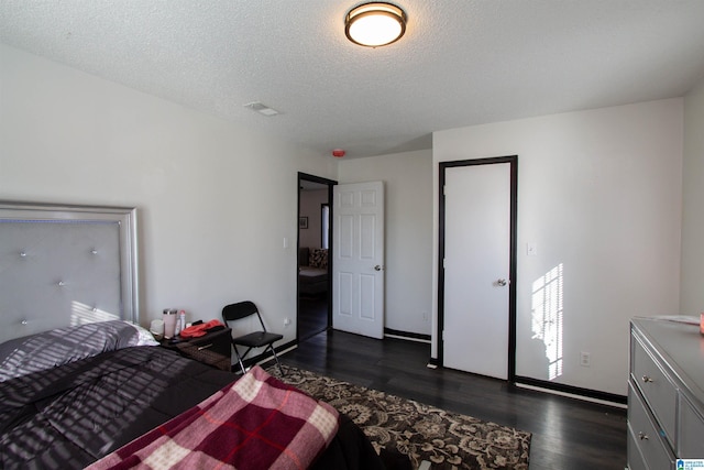 bedroom with a textured ceiling and dark hardwood / wood-style flooring