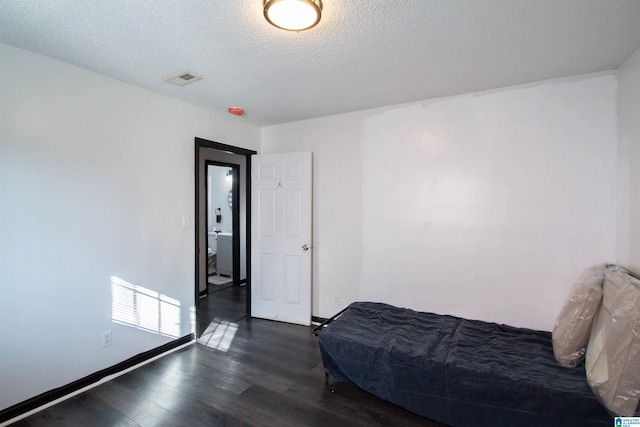 bedroom with a textured ceiling and dark hardwood / wood-style floors