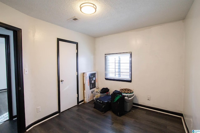 interior space featuring a textured ceiling and dark hardwood / wood-style floors