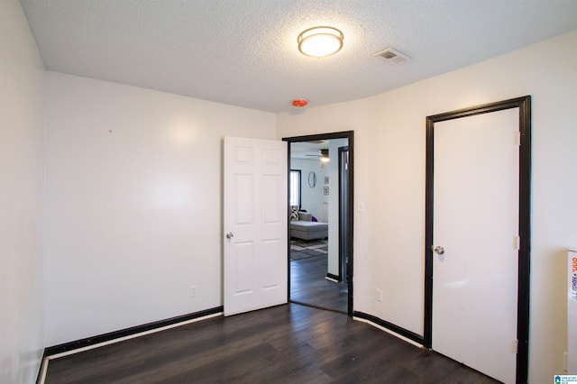 unfurnished bedroom with dark wood-type flooring and a textured ceiling