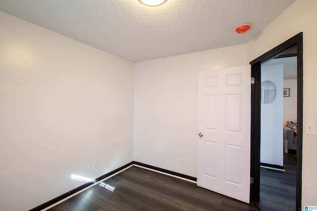 spare room featuring a textured ceiling and dark wood-type flooring