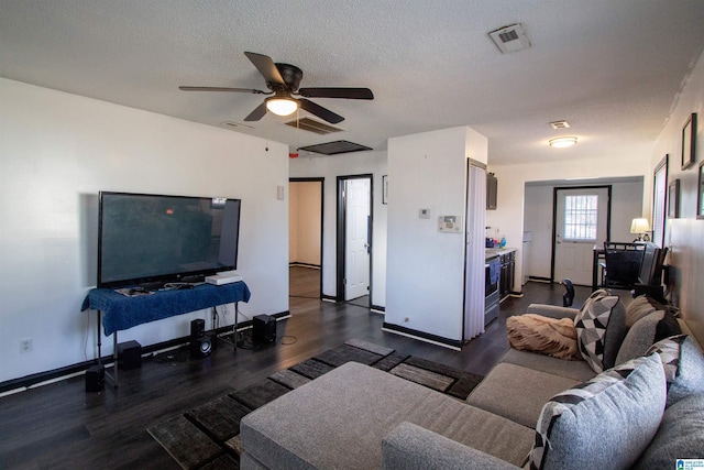 living room with dark wood-type flooring, a textured ceiling, and ceiling fan