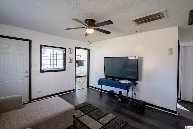 living room with a textured ceiling, ceiling fan, and dark hardwood / wood-style floors