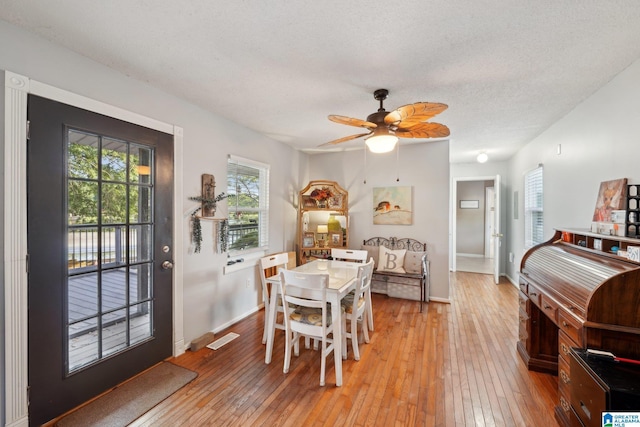 dining room with a textured ceiling, ceiling fan, and light hardwood / wood-style flooring