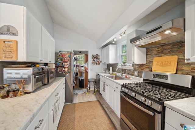 kitchen featuring sink, stainless steel appliances, wall chimney range hood, and white cabinets